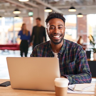 Man smiling while working on laptop in office