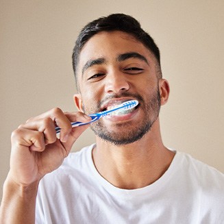 Man smiling while brushing his teeth