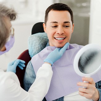 Man smiling at reflection in mirror with dentist