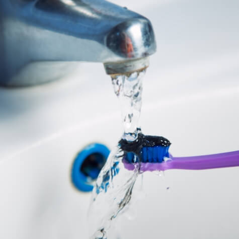 Rinsing off a toothbrush with blue bristles