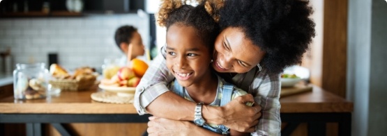 Woman hugging her daughter in the kitchen