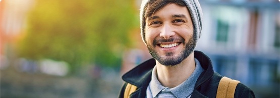 Bearded man in a beanie smiling outside