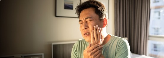 Man with tooth pain sitting on bed