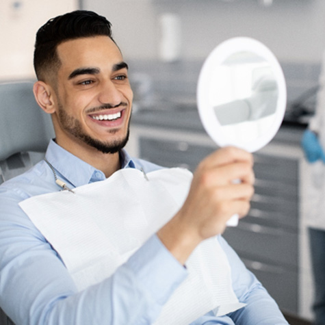 Man smiling at reflection in mirror in treatment chair