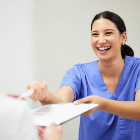 Dentist handing patient forms on a clipboard