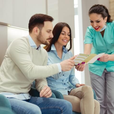 Dental team member showing two patients a pamphlet