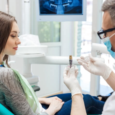 Dentist showing patient a dental implant