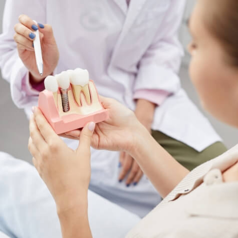 Woman looking at model of dental implant