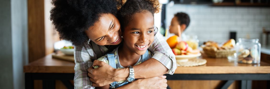 Parent hugging child in busy kitchen