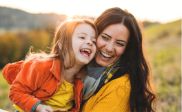 Woman outside in field hugging little girl