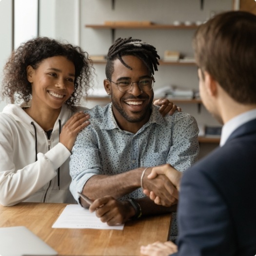 Two people shaking hands with dental team member