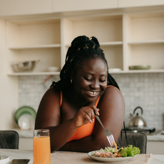 Woman smiling while eating in kitchen